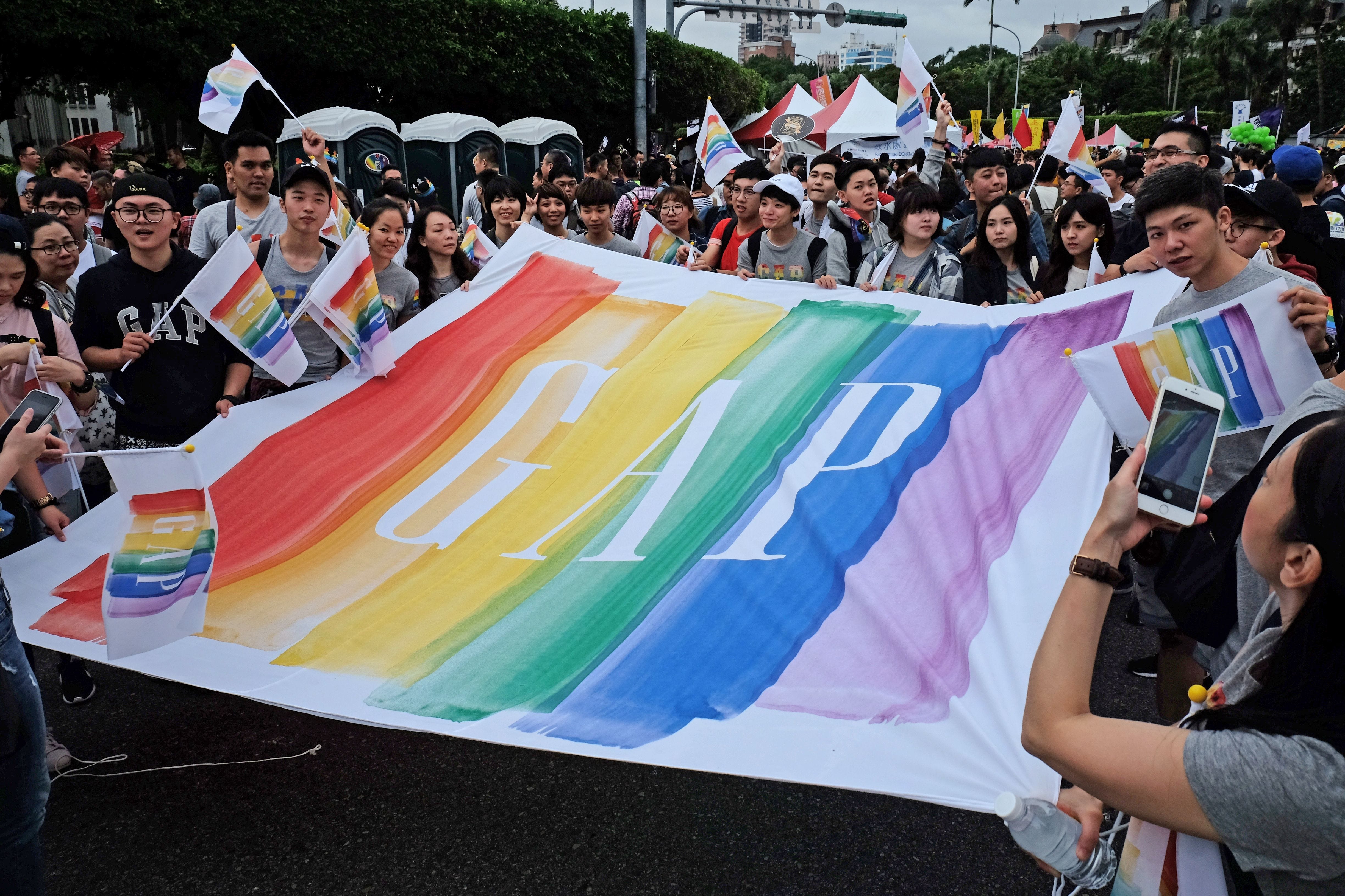 Employees of the GAP clothing chain pose with a banner during the annual Taiwan lesbian, gay, bisexual and transgender pride parade in Taipei on October 29, 2016.