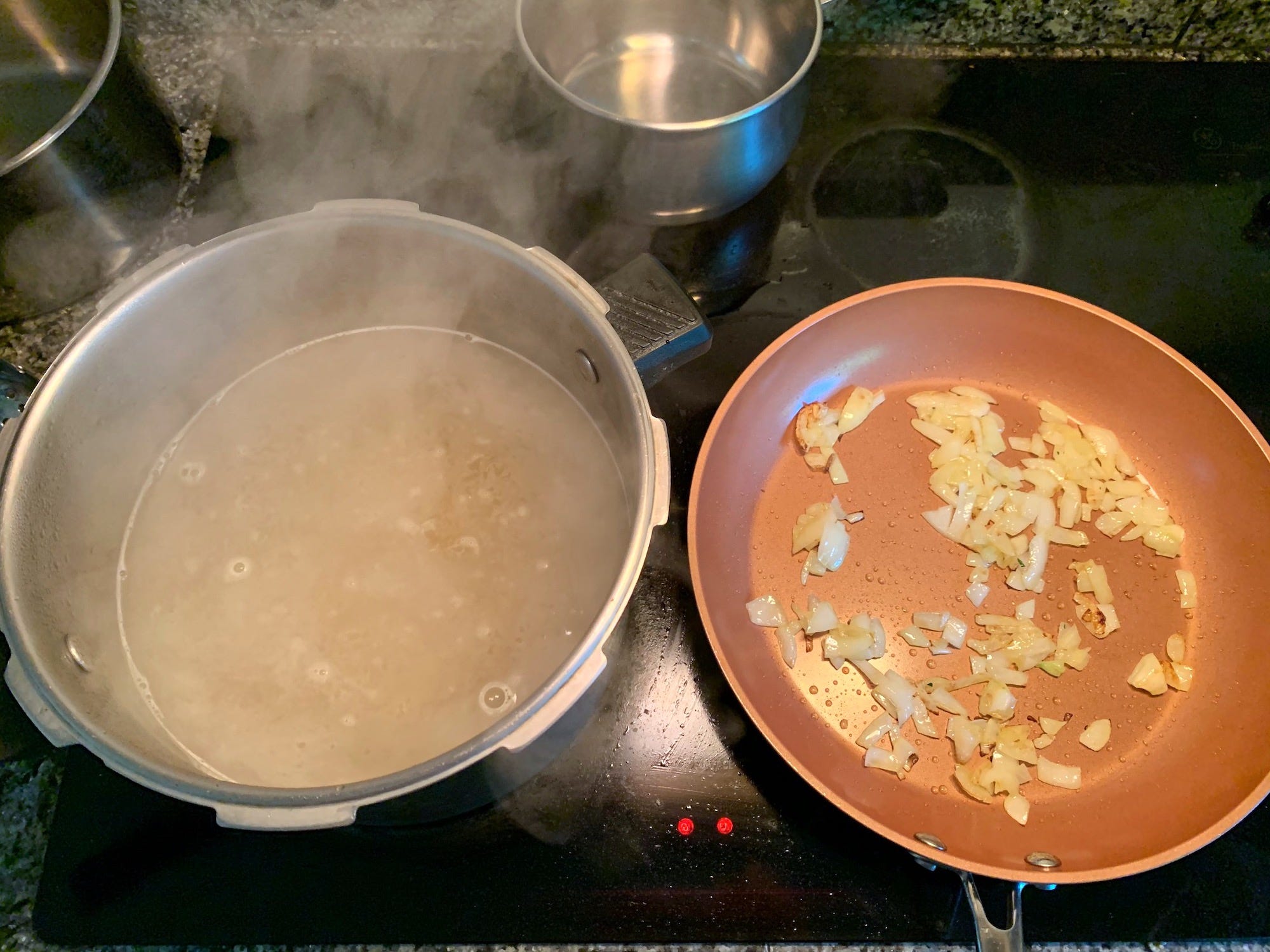 Onions in a pan and a pot of boiling water for pasta