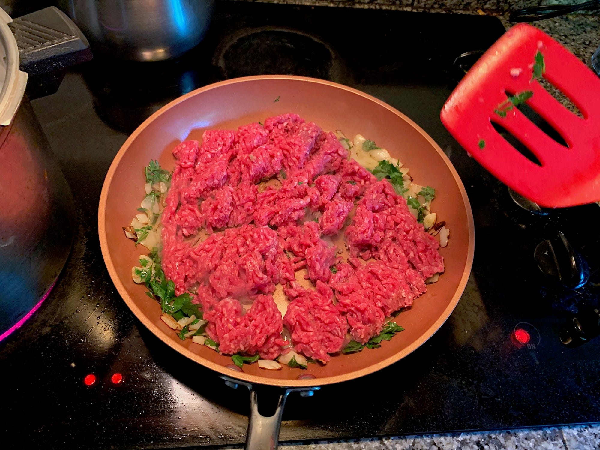 Ground beef in pan with onions, parsley