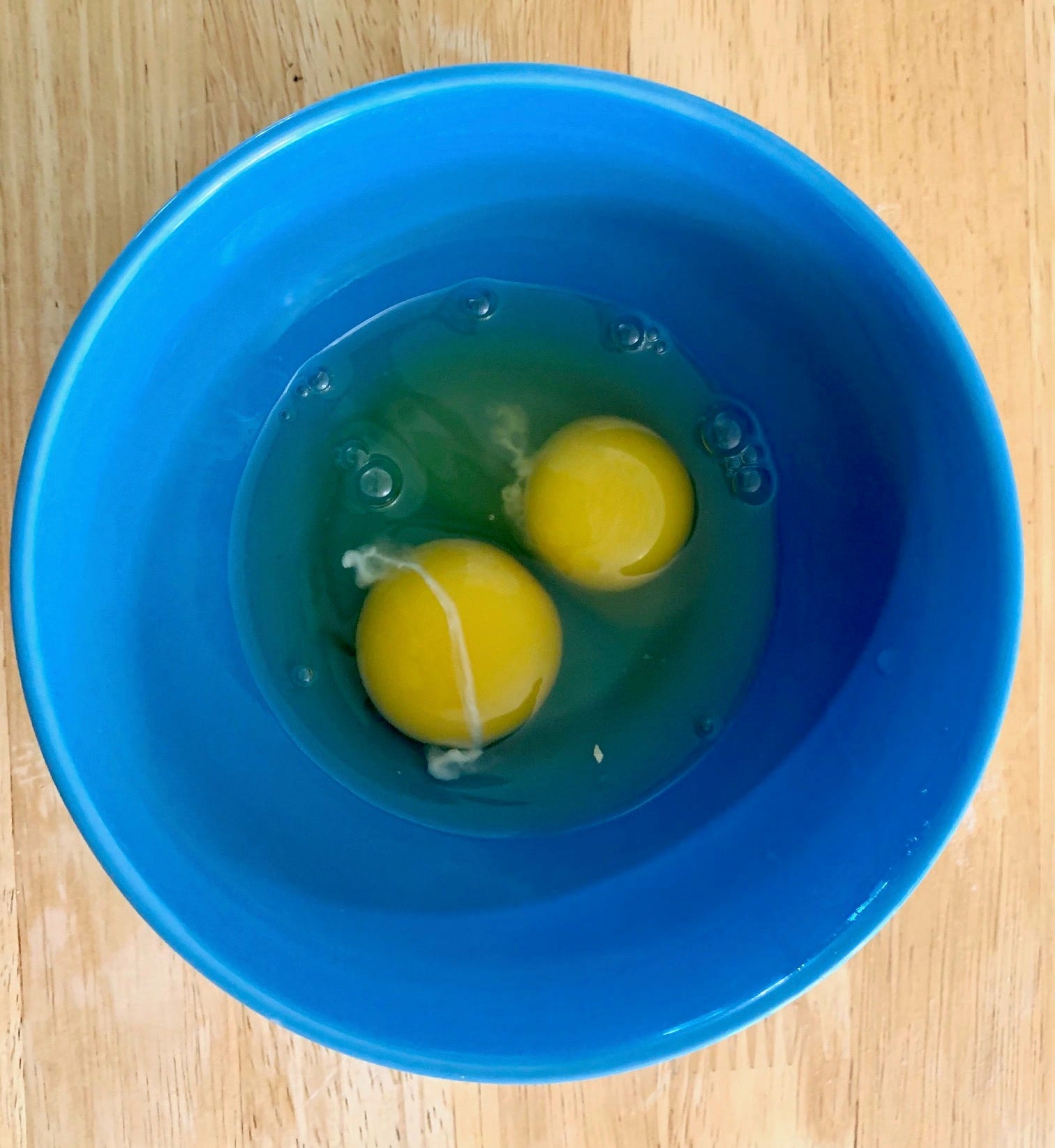 Two cracked eggs in a blue bowl