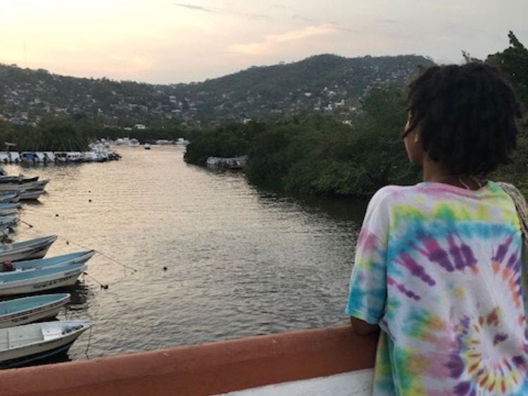The author wearing a tie-dye shirt looking out over a river in Zihuatanejo.