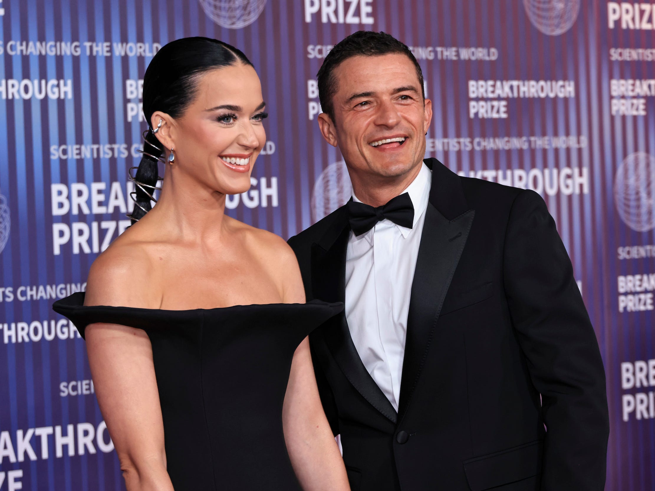 Katy Perry and Orlando Bloom smile together on the red carpet.