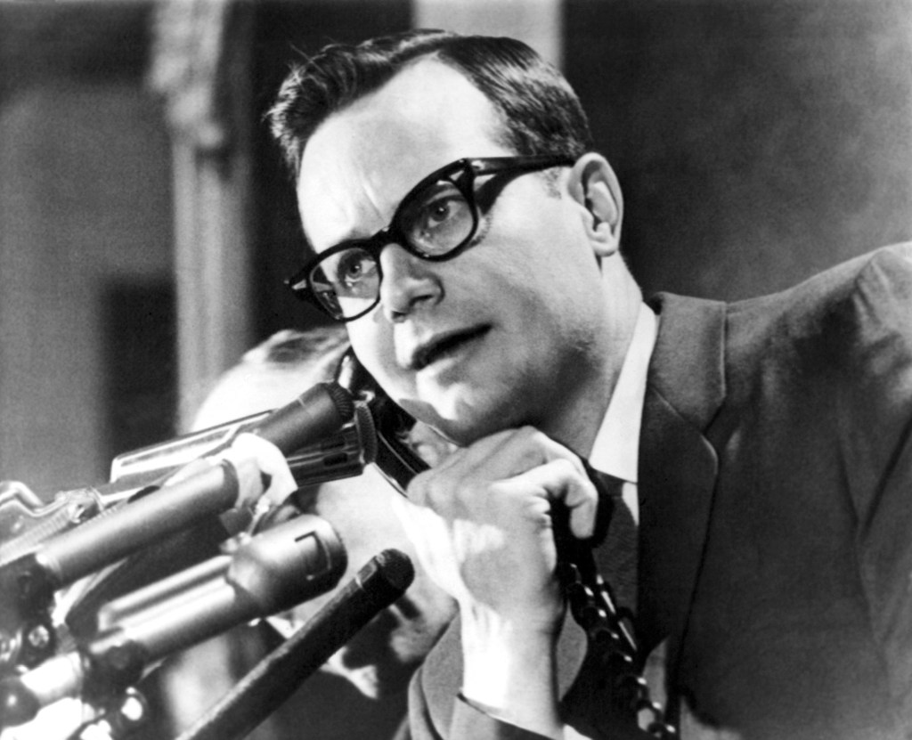 Black and white photo of Bill Moyers on the phone at a press briefing.