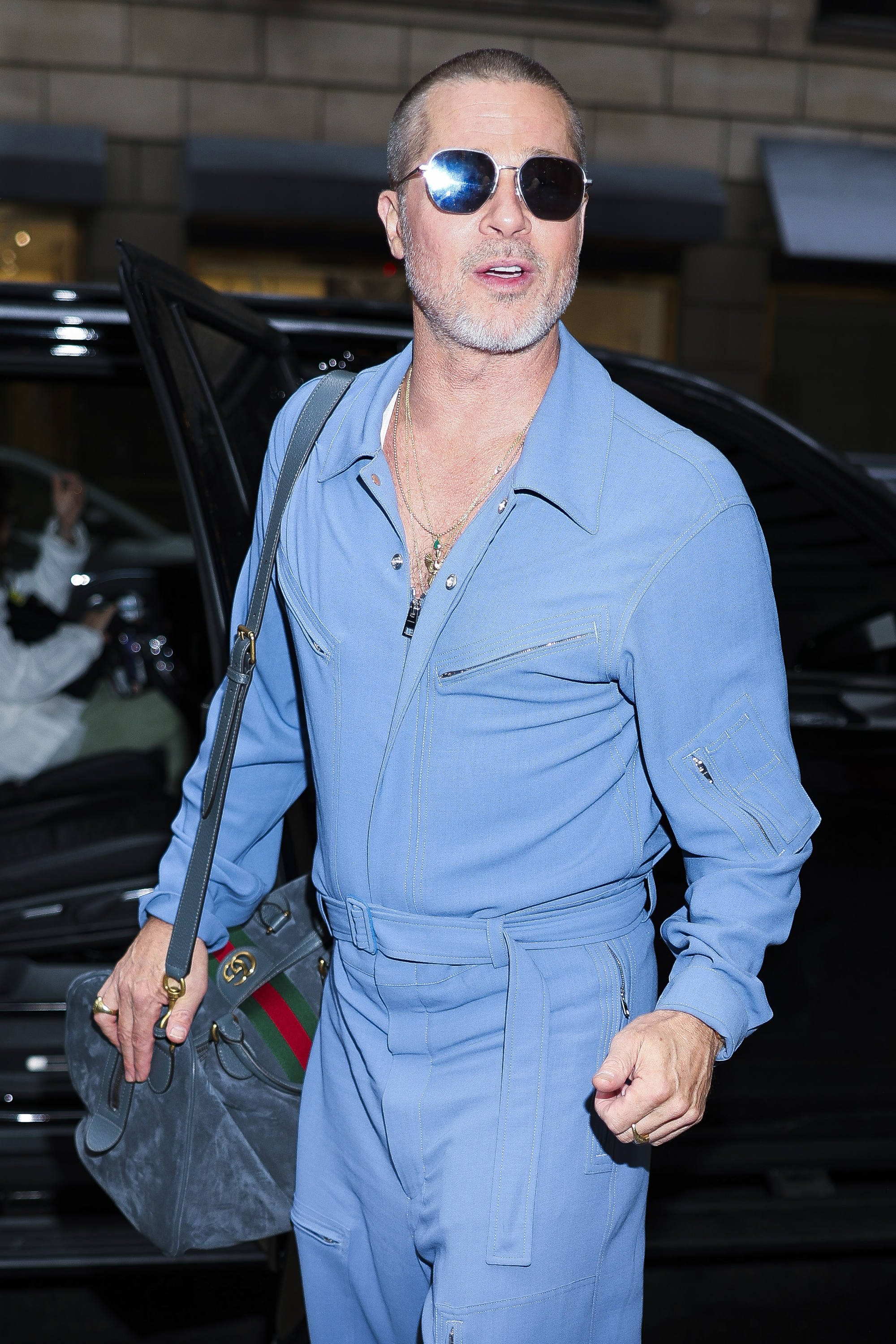 Brad Pitt in a blue shirt and sunglasses at night. 