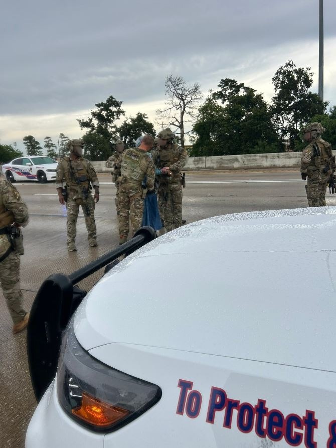 Police officers apprehending a woman on a highway.