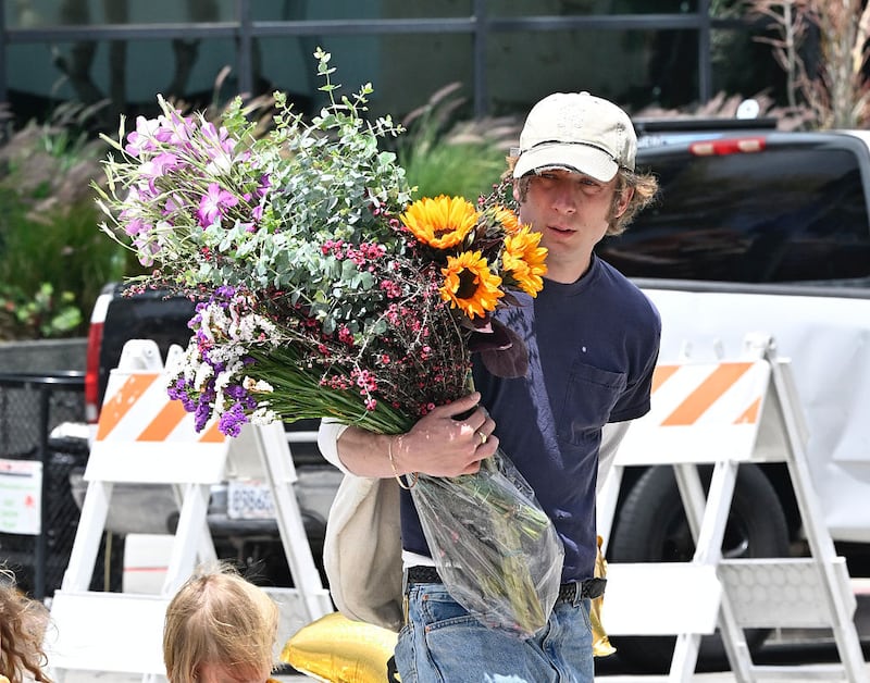 Jeremy Allen White in public with his daughters, holding a bouquet of flowers.