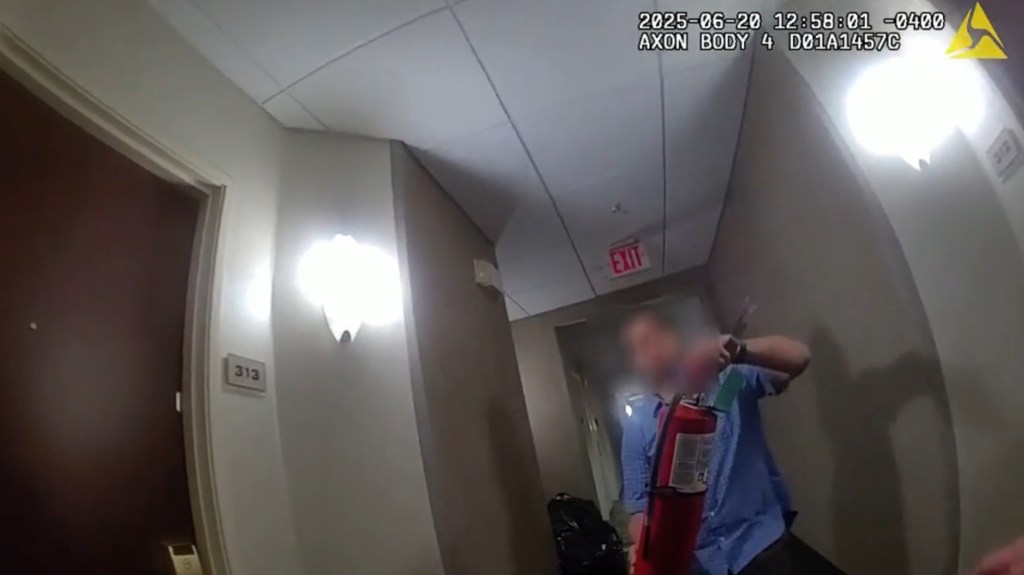 A hotel employee brings a fire extinguisher to the cops outside the room.