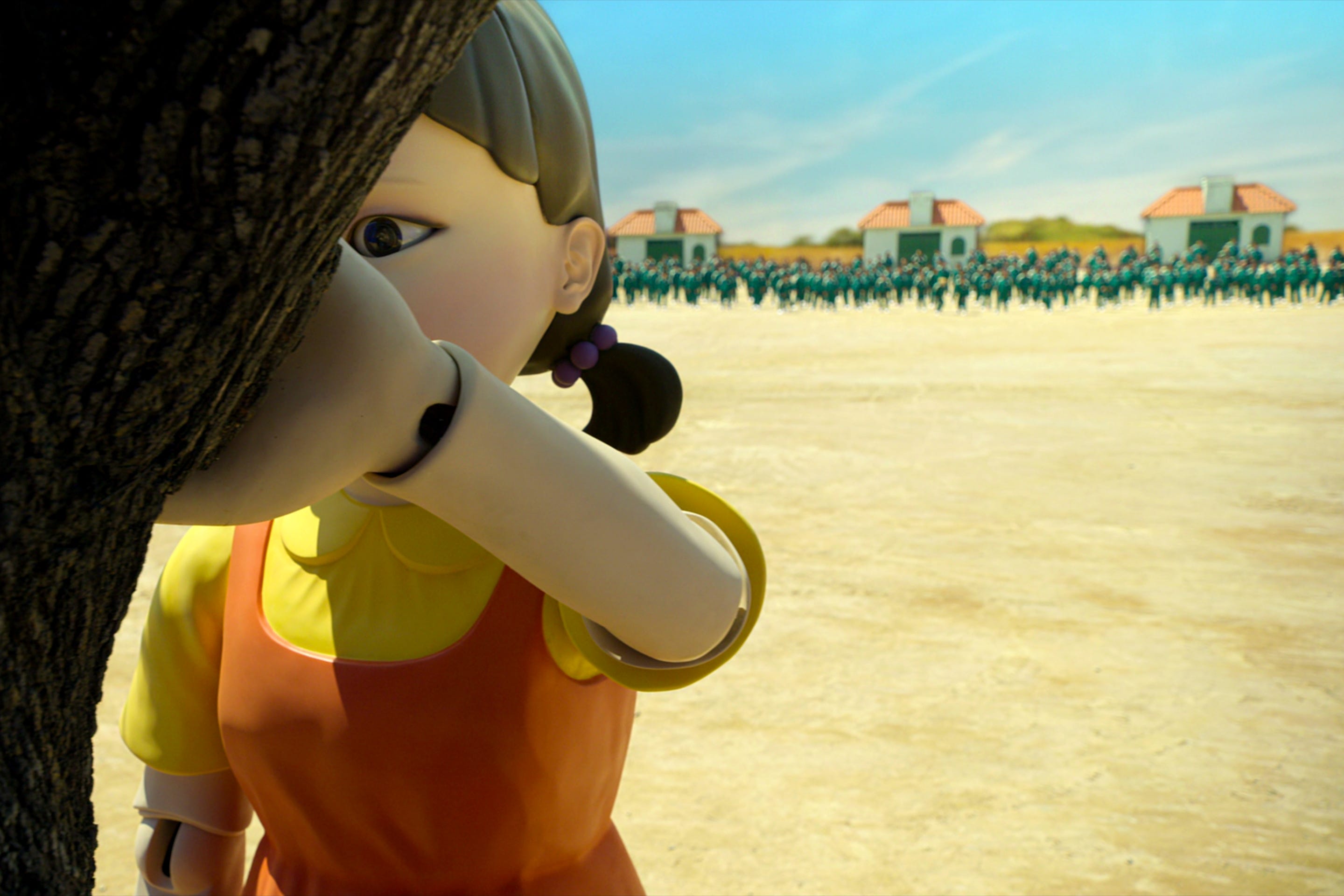 A giant doll holding a tree with its back turned to hundreds of people.
