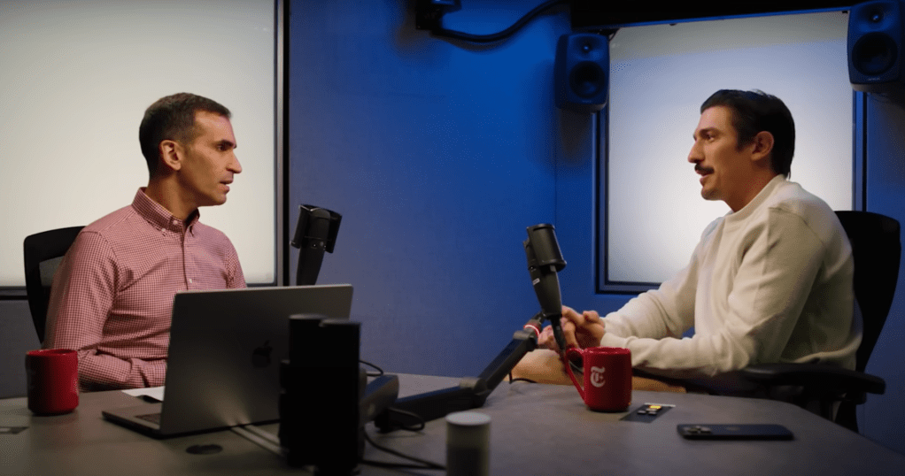Two men sitting in a podcast studio, talking into microphones.