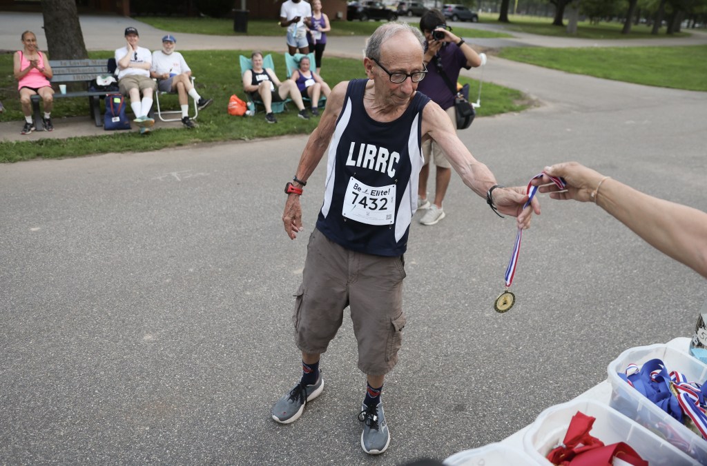 David Frisone, 80, receives a medal after participating in a weekly 5K at Eisenhower Park in East Meadow, N.Y. 