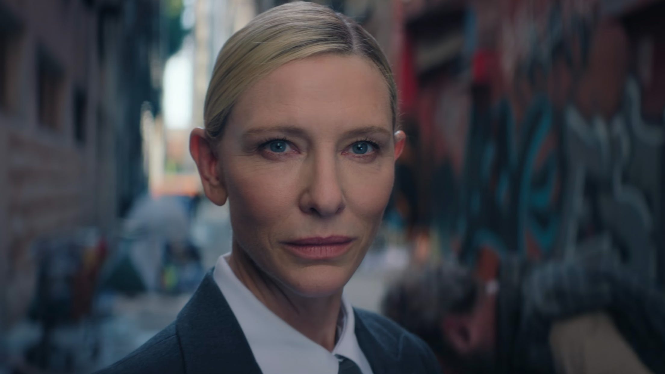 A screengrab of "Squid Game" showing Cate Blanchett wearing a suit in an alleyway.