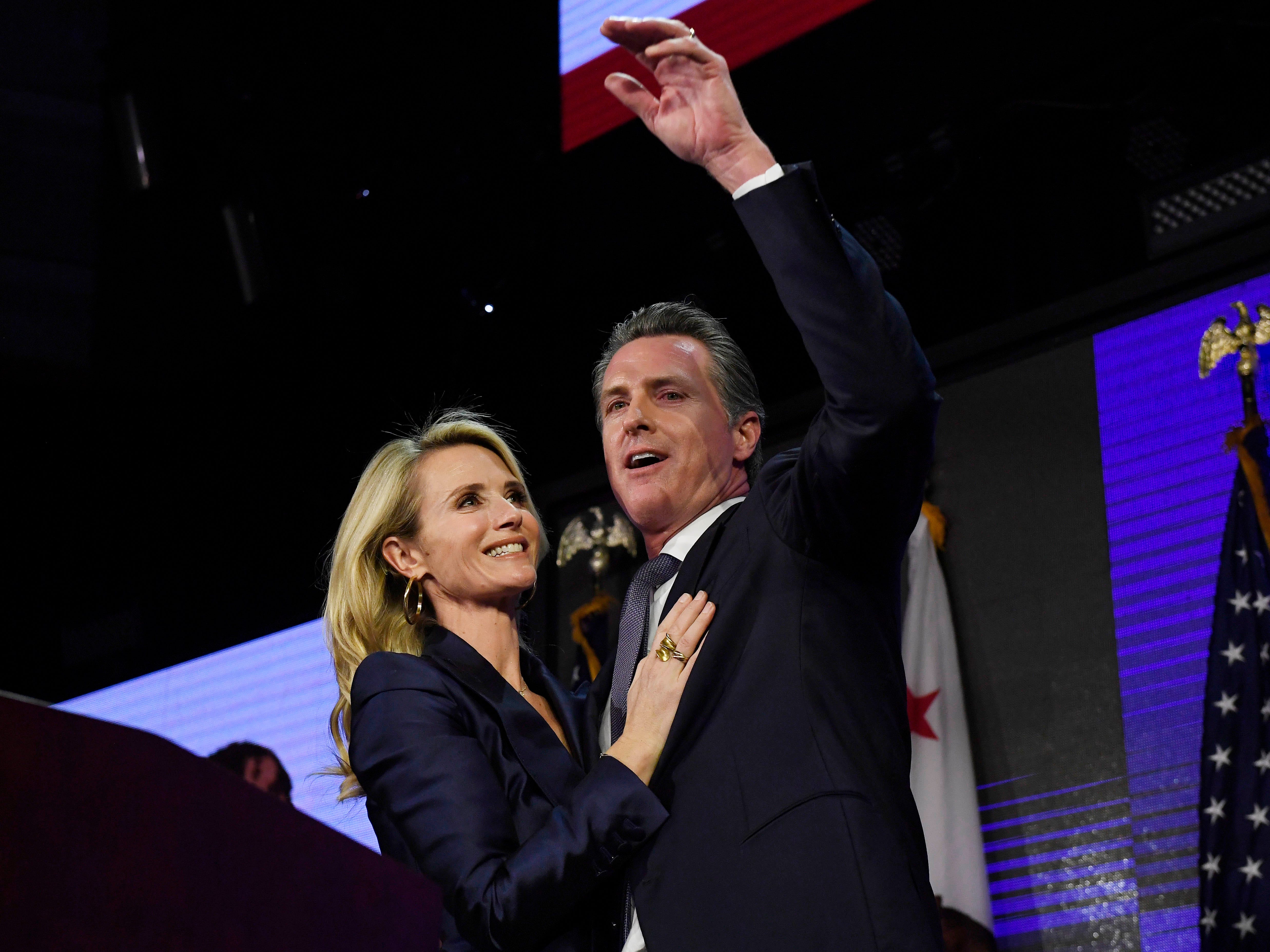 Democratic gubernatorial candidate Gavin Newsom and his wife Jennifer Siebel Newsom wave to supporters during an election night event.