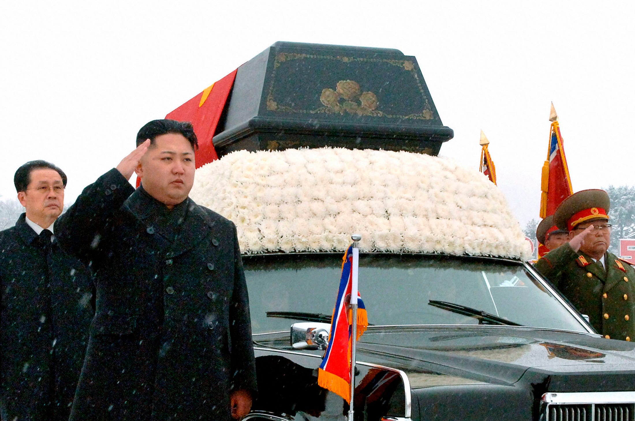 Kim Jong Un salutes as he and his uncle Jang Song Thaek (L) accompany the hearse carrying the coffin of late North Korean leader Kim Jong-il during his funeral procession in Pyongyang in this photo taken by Kyodo December 28, 2011. North Korea's military staged a huge funeral procession on Wednesday in the snowy streets of the capital Pyongyang for its deceased
