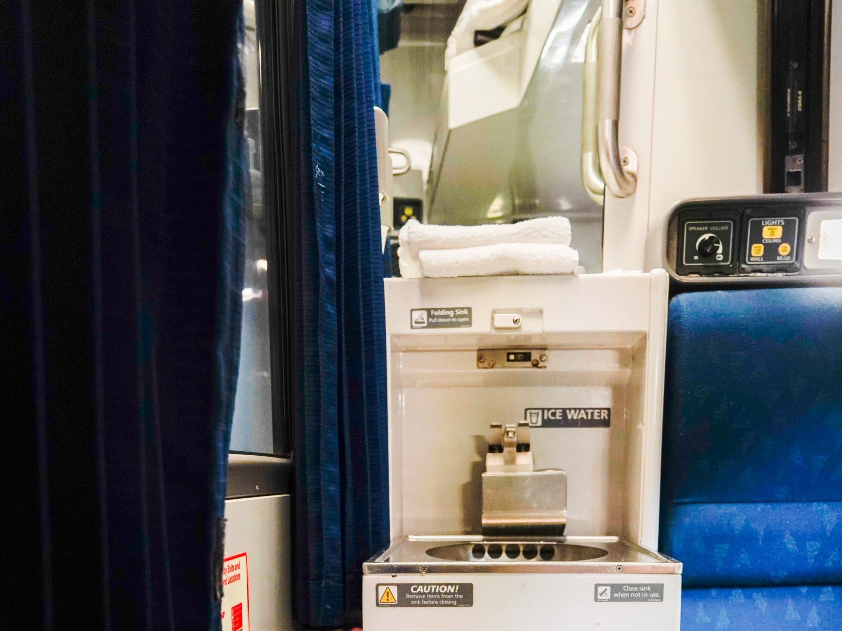 A pull-out sink below a mirror in an Amtrak roomette cabin