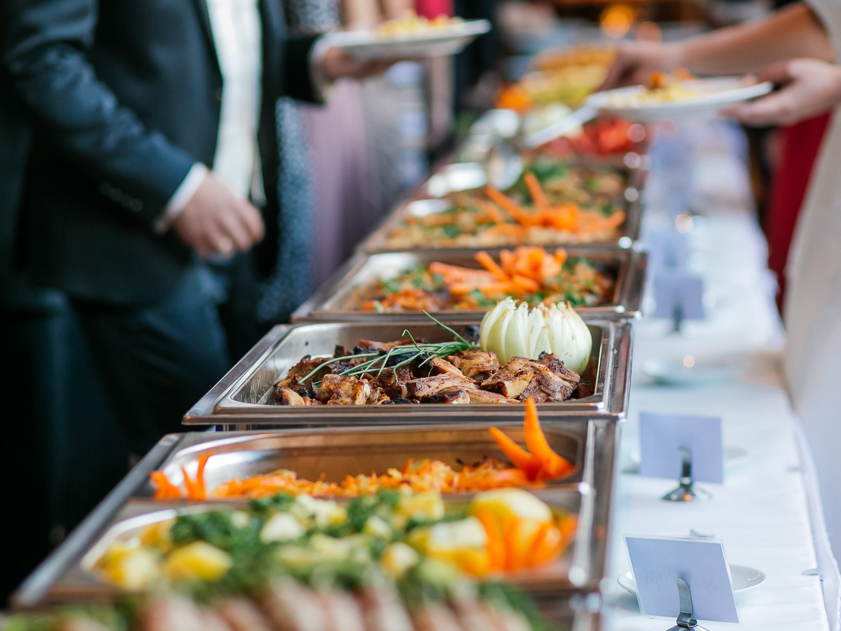 people serve themselves food from a buffet at a wedding