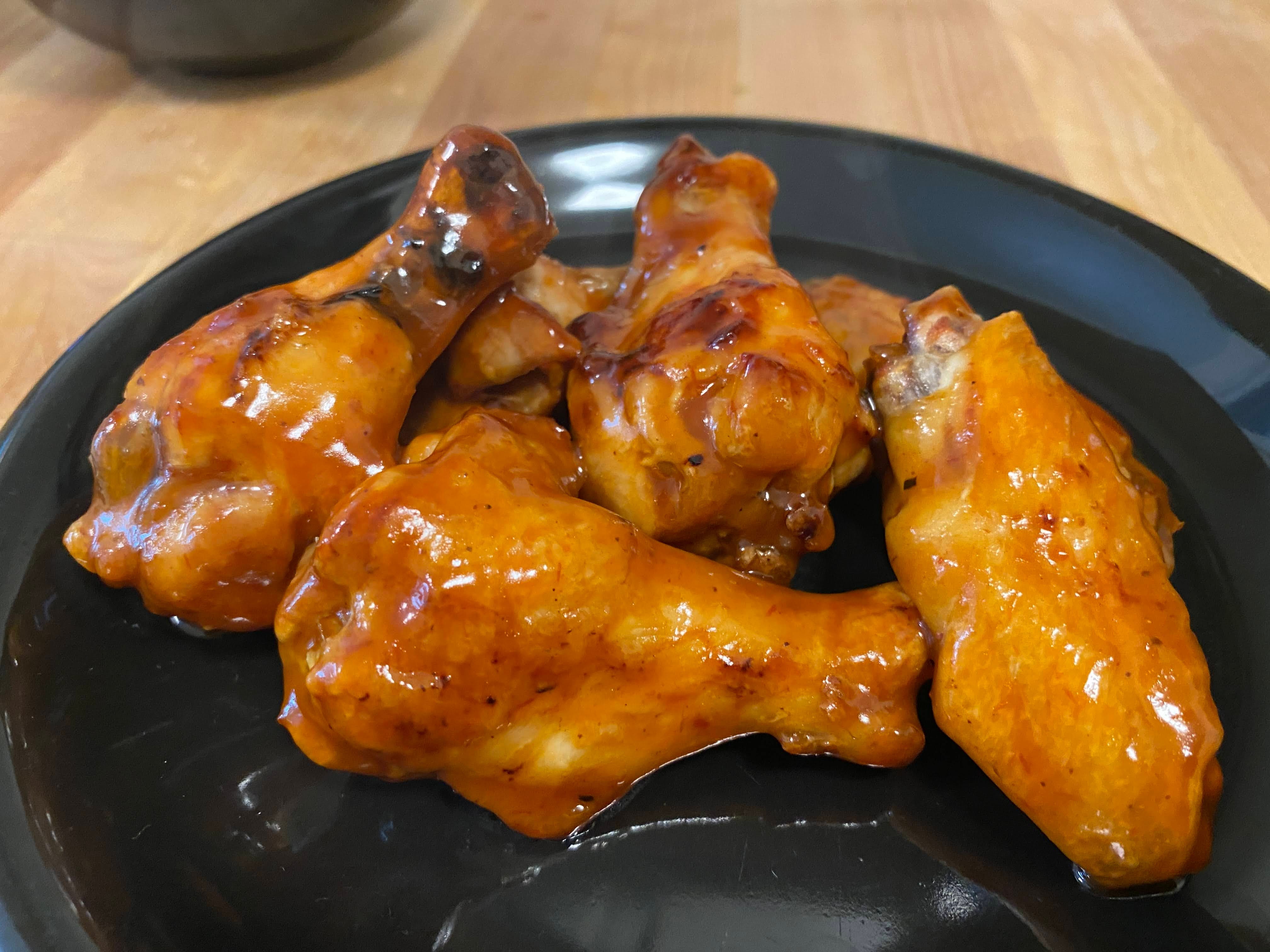 A photo of tossed chicken wings on a plate