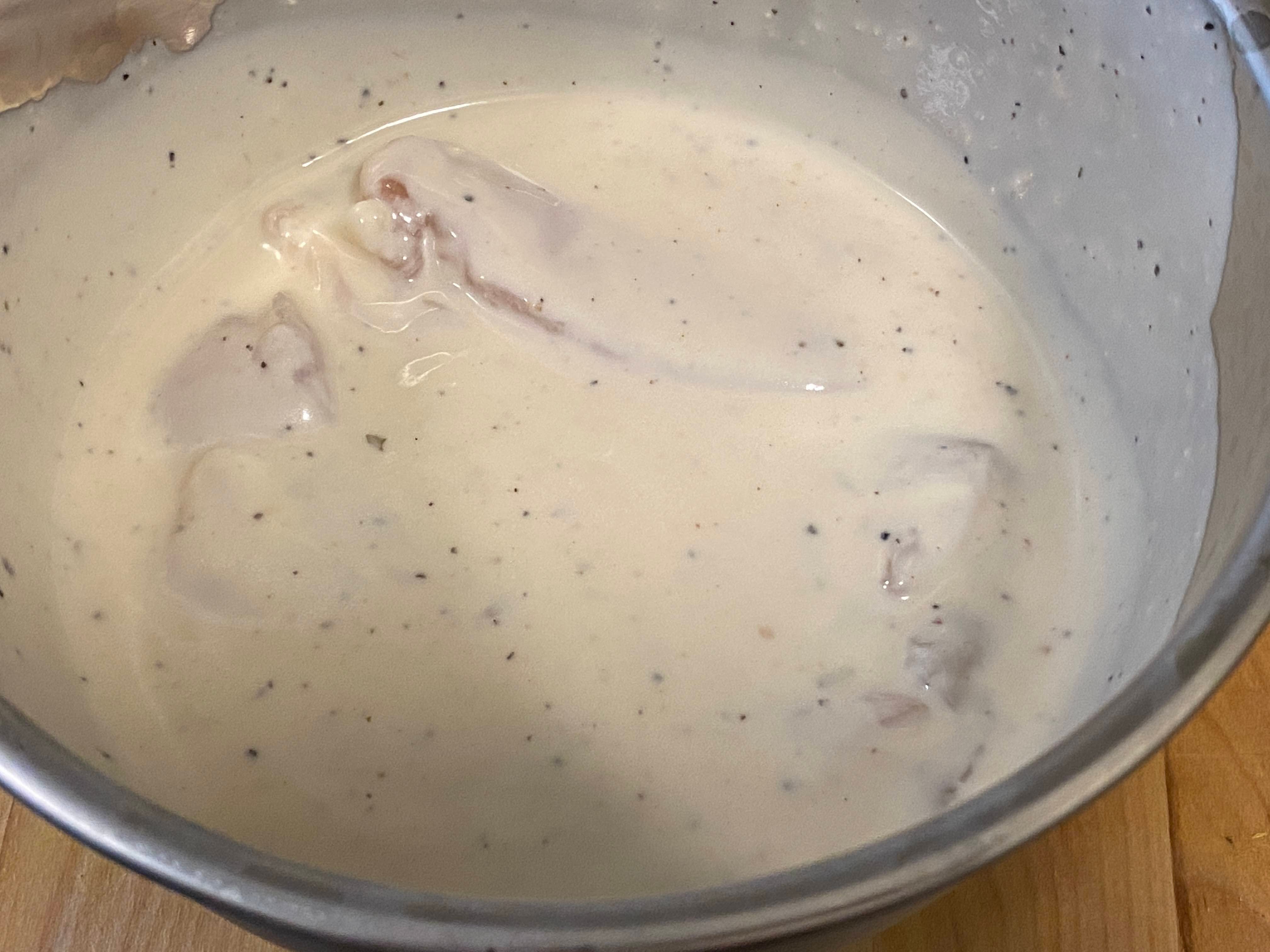 A photo of chicken tenderloins in a bowl of ranch marinade