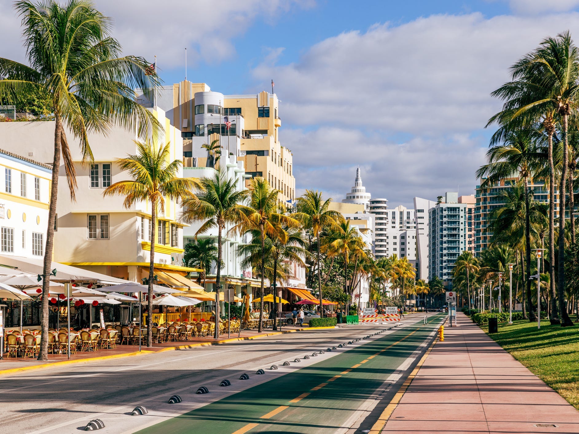 Art-deco hotels and palm trees along a street in Miami.