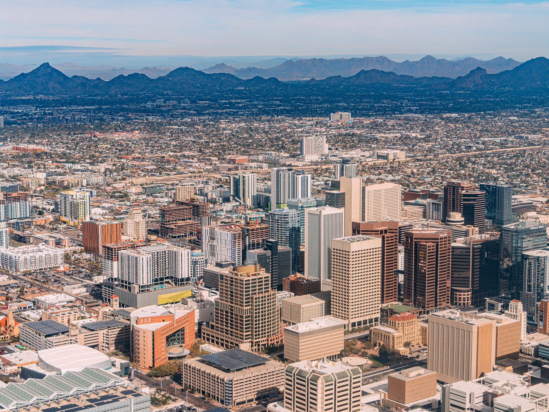An aerial view of skyscrapers in Phoenix with mountains in the background.
