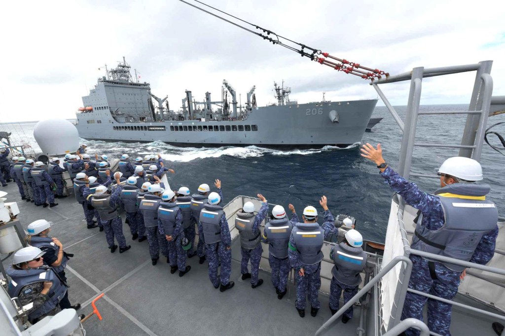 Crewmembers of Japanese Maritime Self Defense Force training vessel JS Kashima wave towards the U.S. Navy oiler USNS Harvey Milk during an exercise in the Virginia Capes