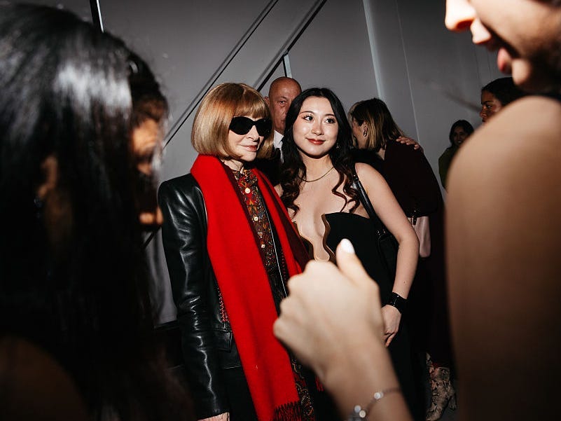 Anna Wintour at an event, posing with a fashion student.