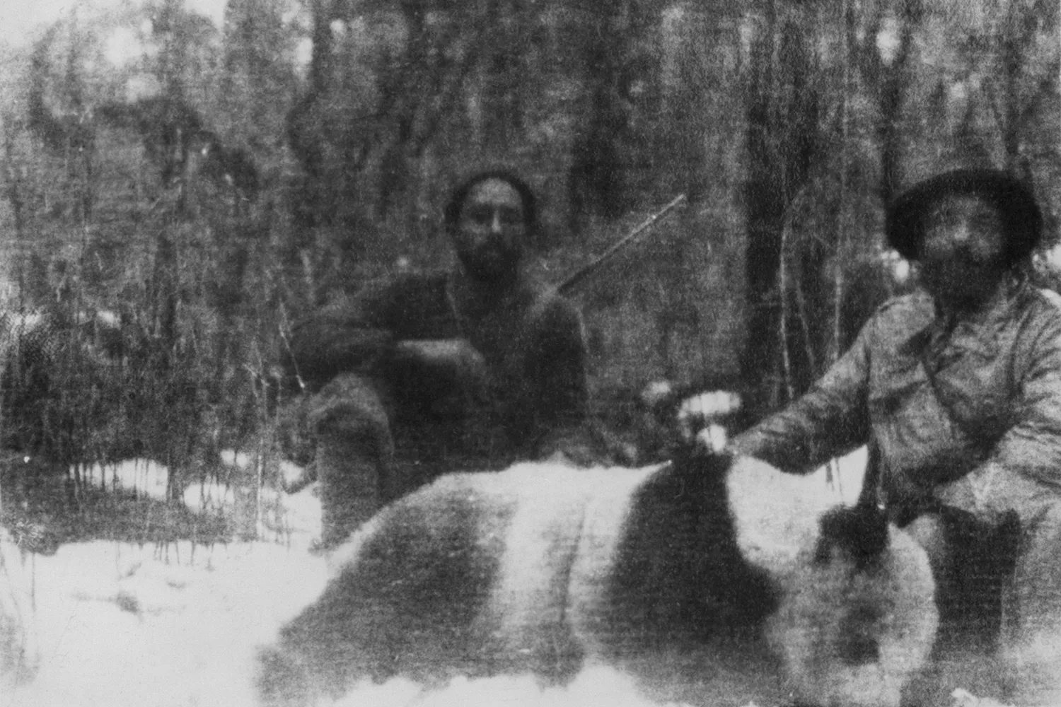 Two hunters pose with a giant panda in this historic photograph.