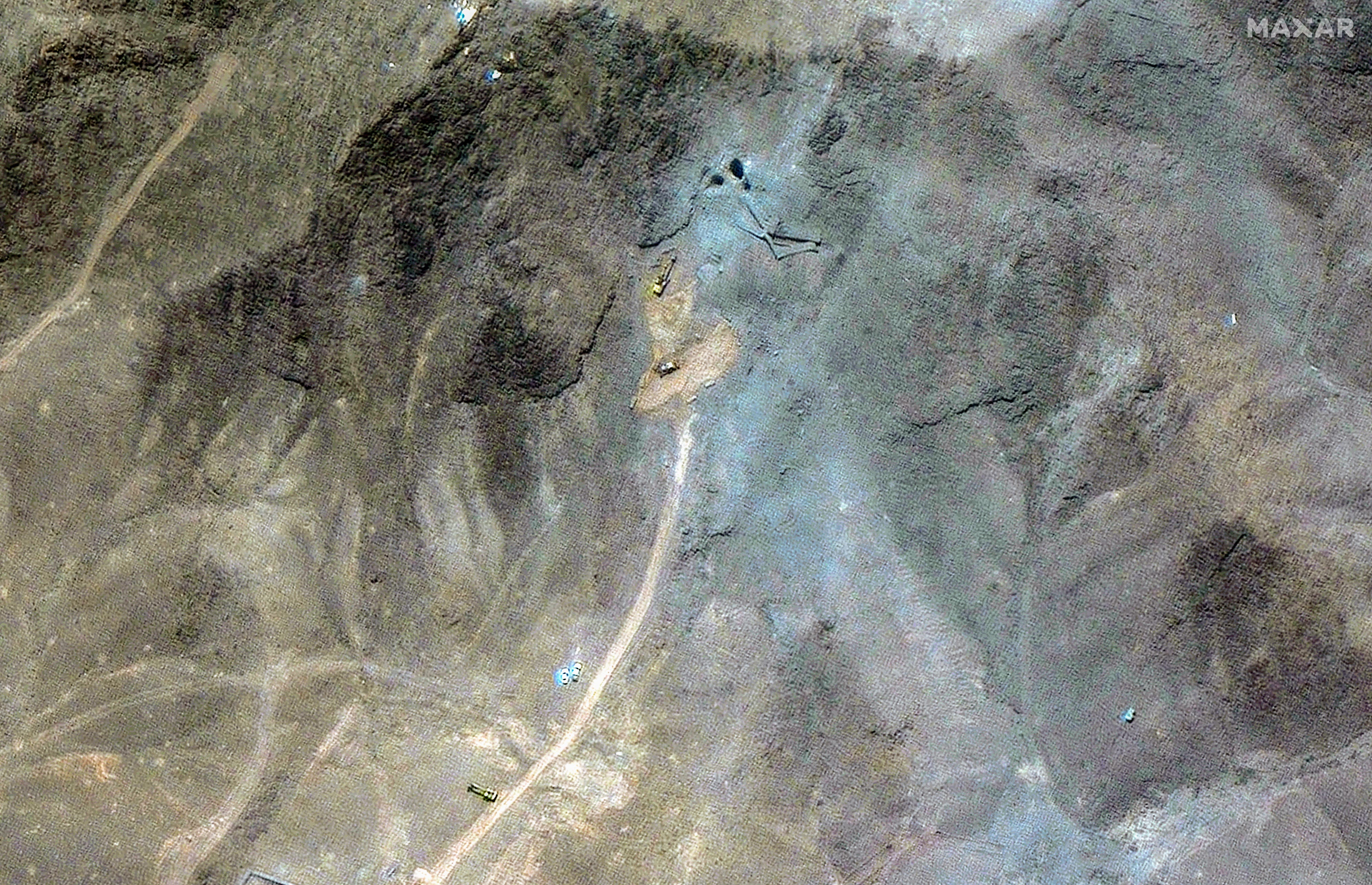 A satellite image shows a close-up of excavators working on a road at Iran's Fordow nuclear facility in the mountains.