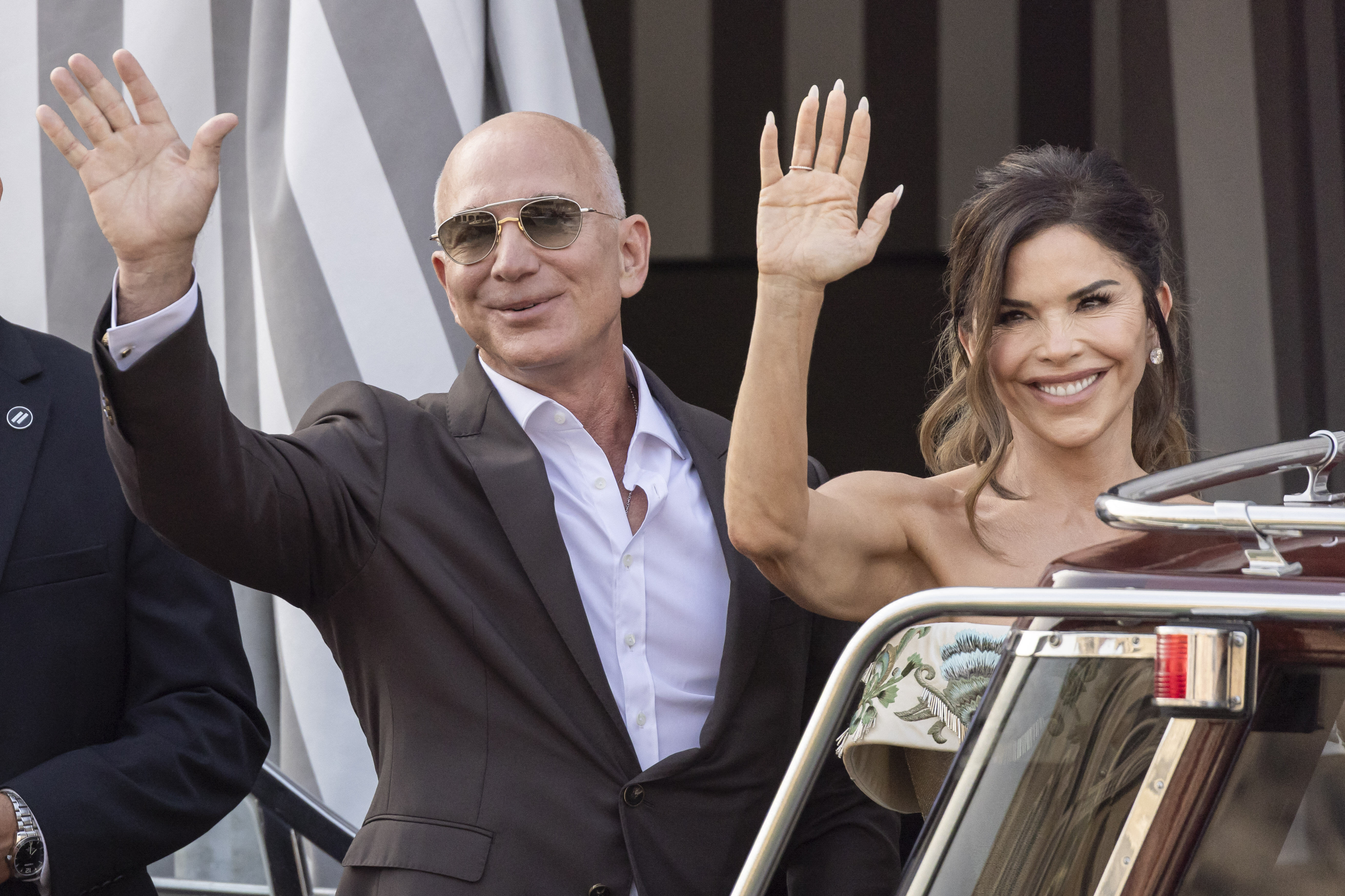 Jeff Bezos and Lauren Sanchez wave. 