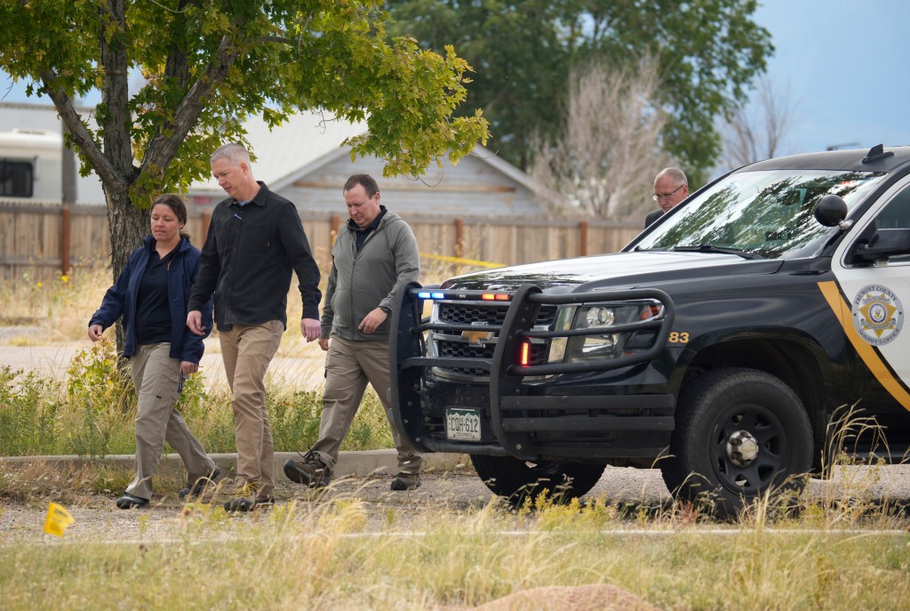 Investigators walk near a police vehicle outside a funeral home.