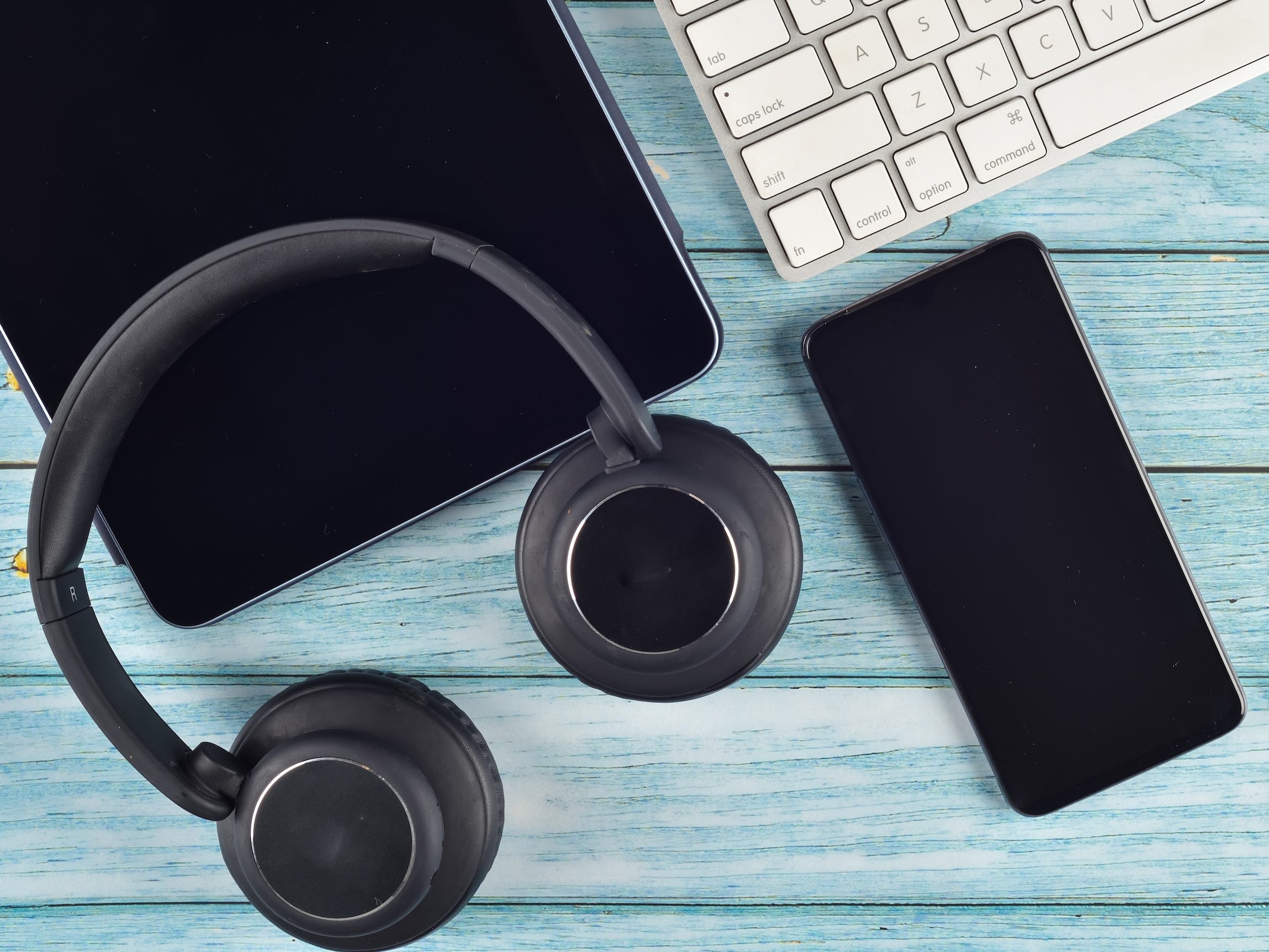Headphones and a cellphone on a blue table.