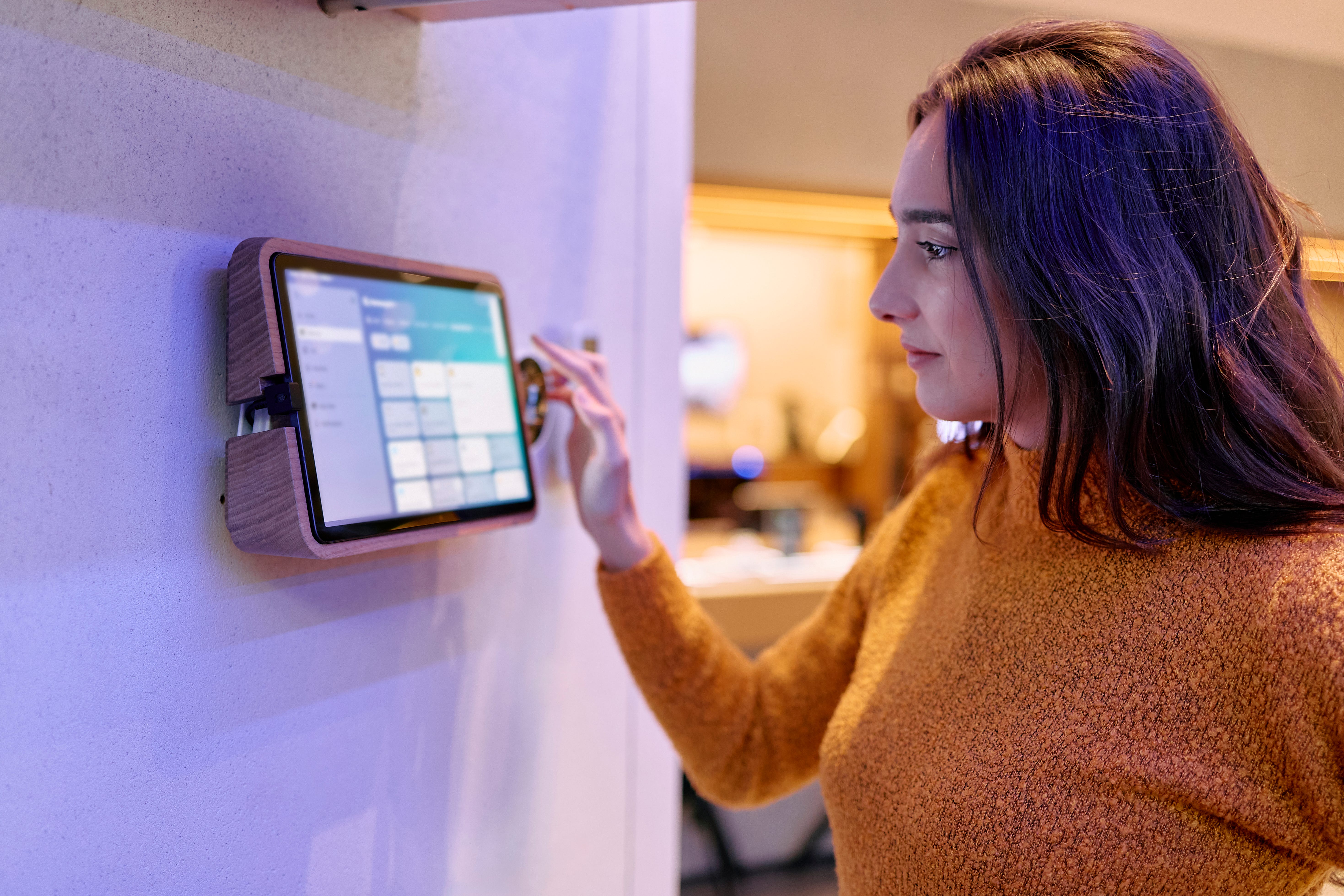 A woman is looking at a device sitting on the wall.