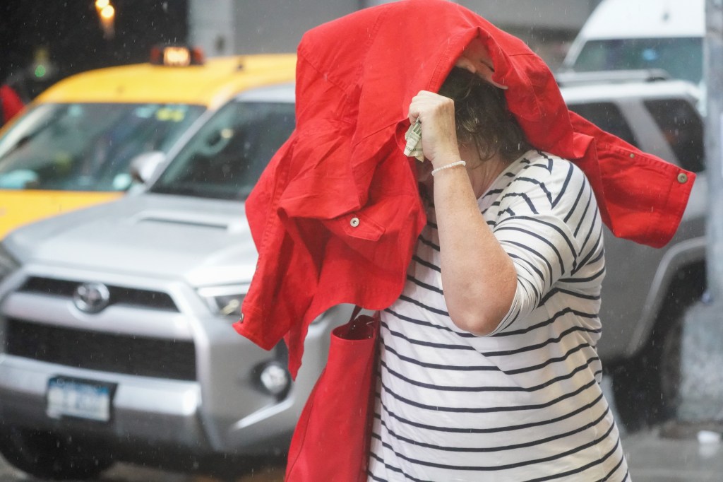 Woman using a red jacket to shield herself from the rain in Times Square, NYC.