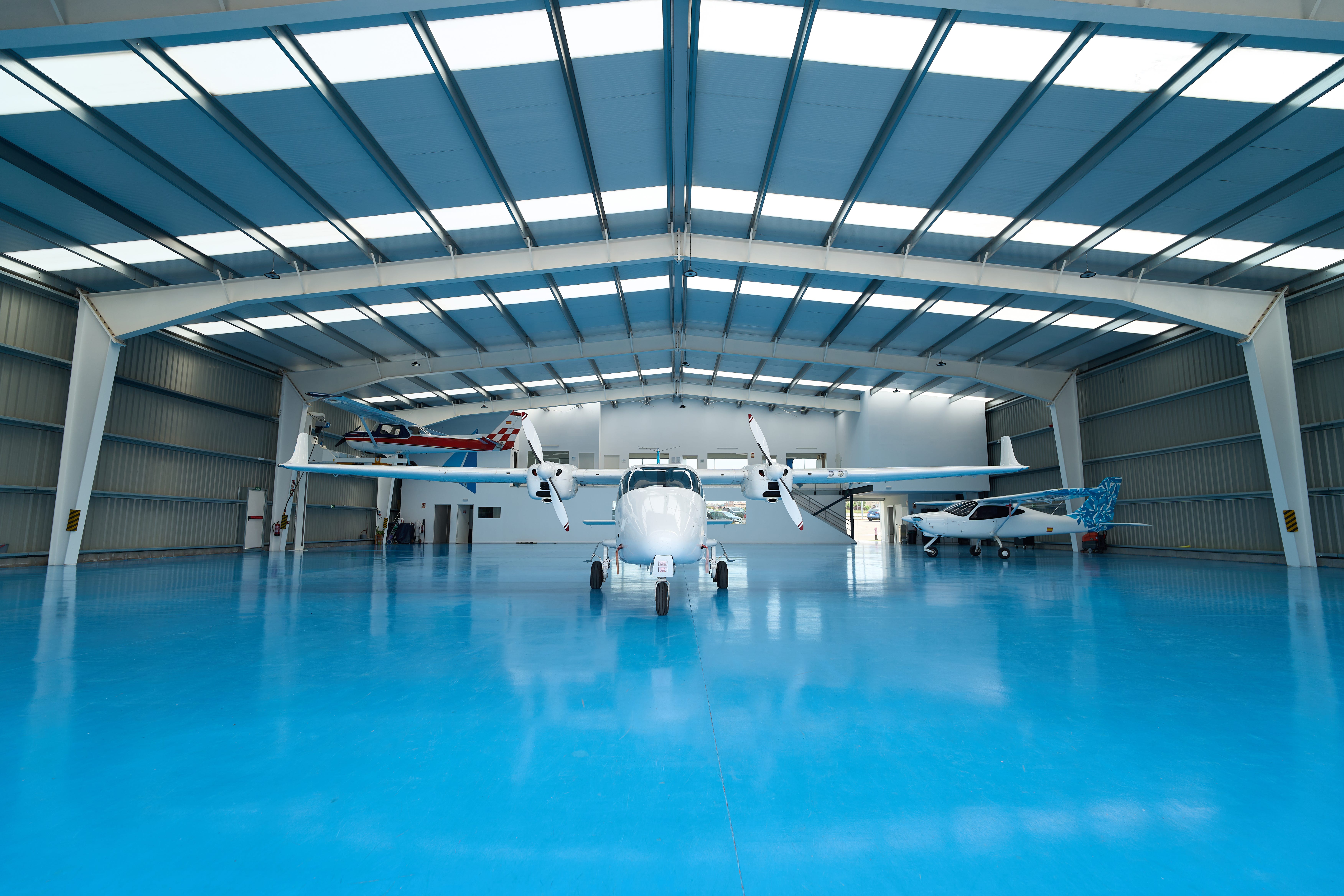 Modern hangar featuring a blue floor, housing training aircraft and facilitating the preparation of future pilots for flight