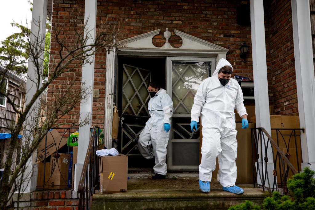 Workers in protective suits outside of the Mill Basin home where an elderly woman was found dead and more than 100 dogs neglected on June 27, 2025