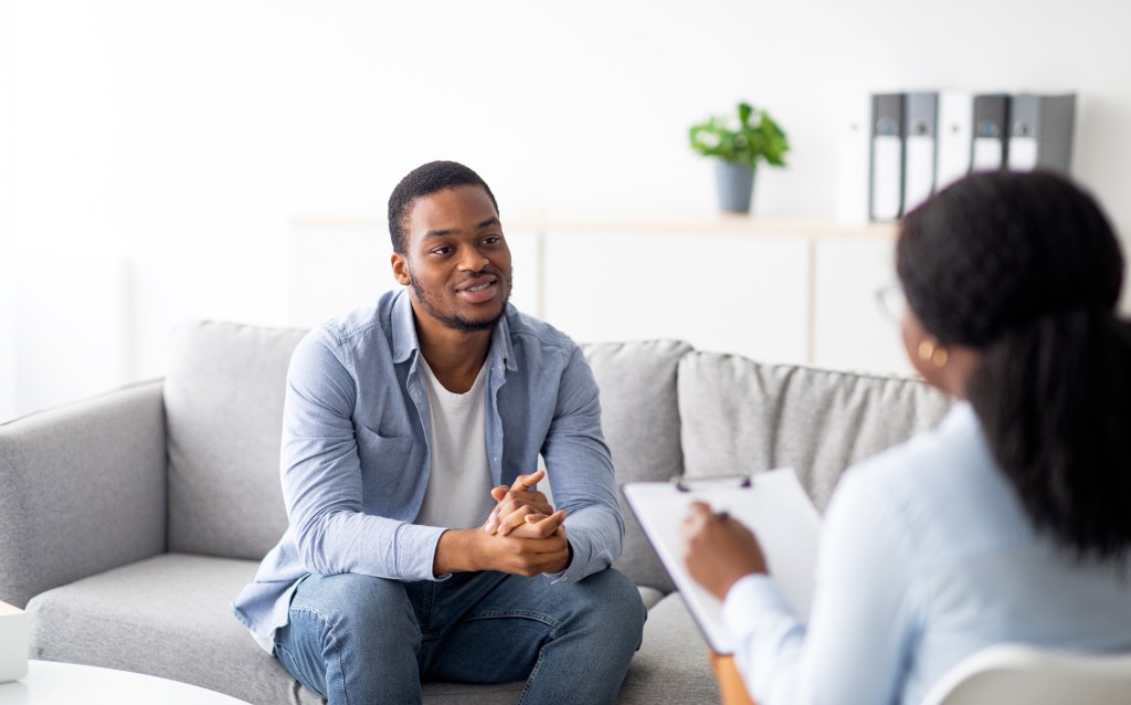 A young Black man talking to his psychologist during a therapy session.