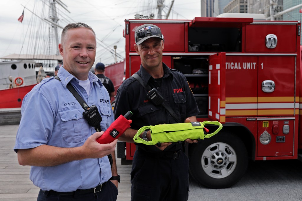 Two FDNY firefighters holding rescue equipment.