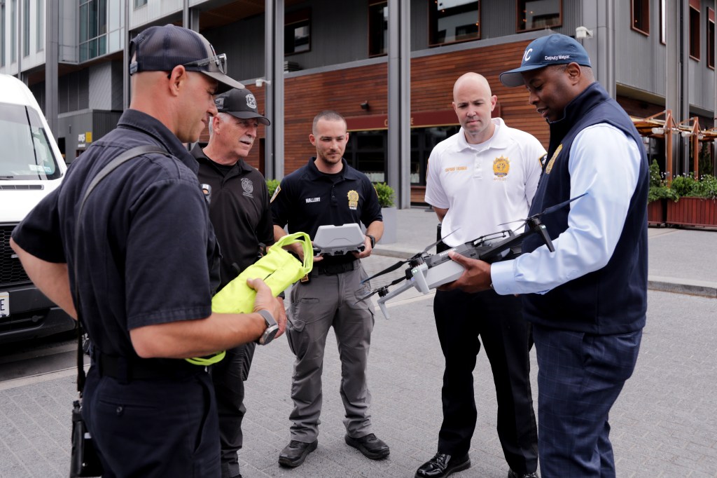 Deputy Mayor Kaz Daughtry and NYPD officers examining a drone.