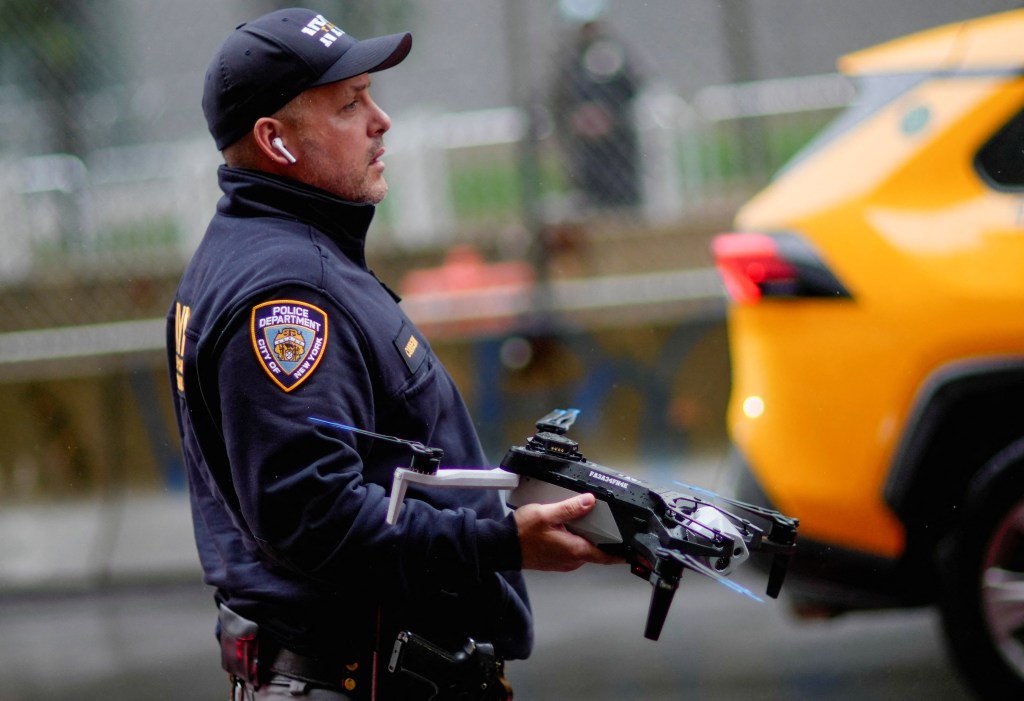 NYPD officer holding a drone at a protest.