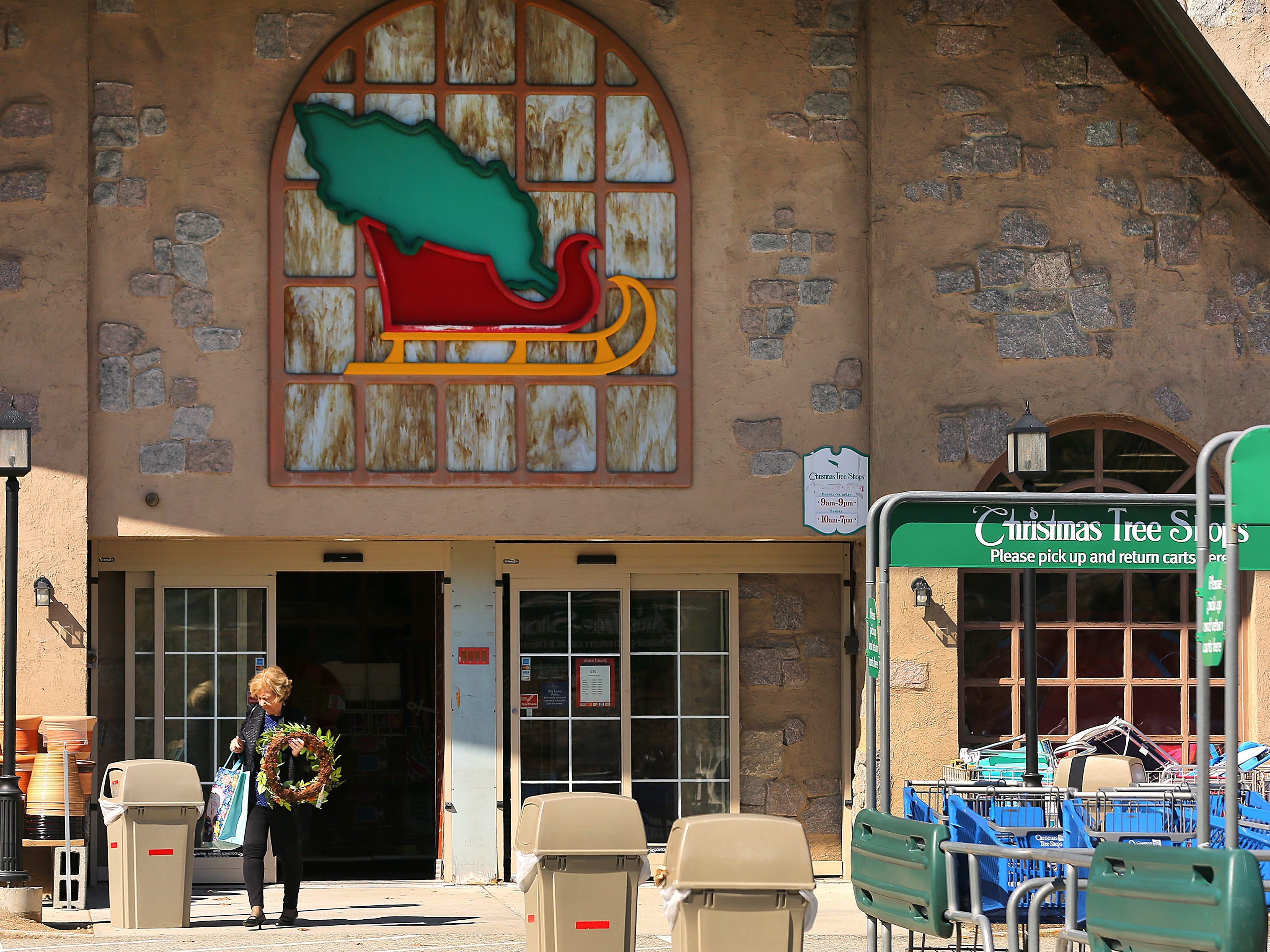 A customer leaves a Christmas Tree Shop in Pembroke, Massachusetts, carrying a holiday wreath and a shopping bag
