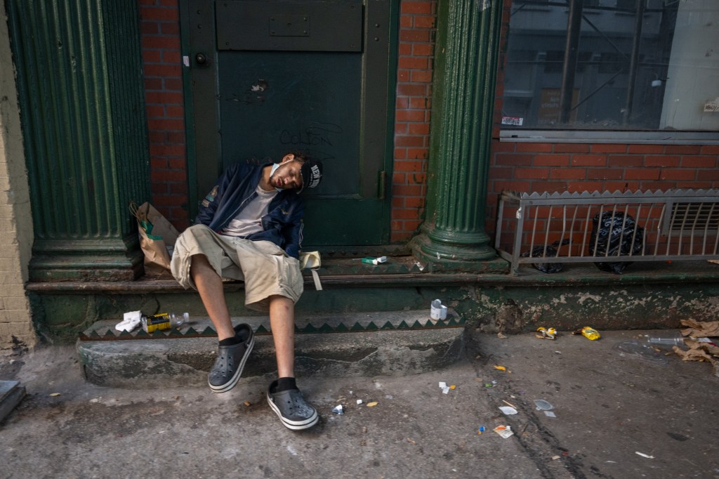 Person sleeping on steps outside a building.