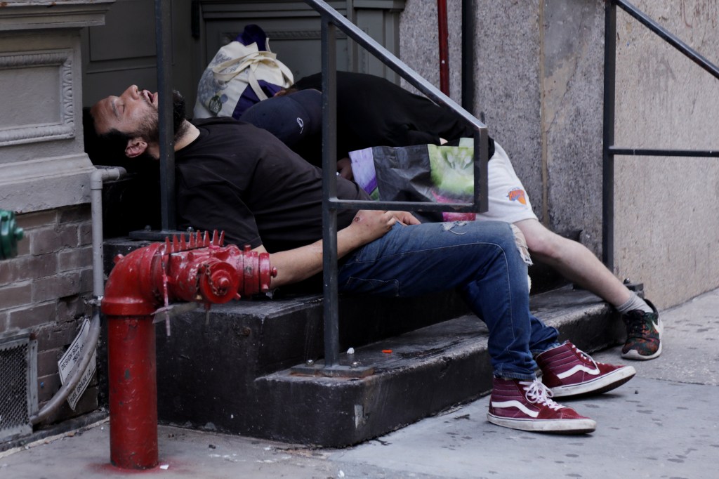 Two people sleeping on a stoop.