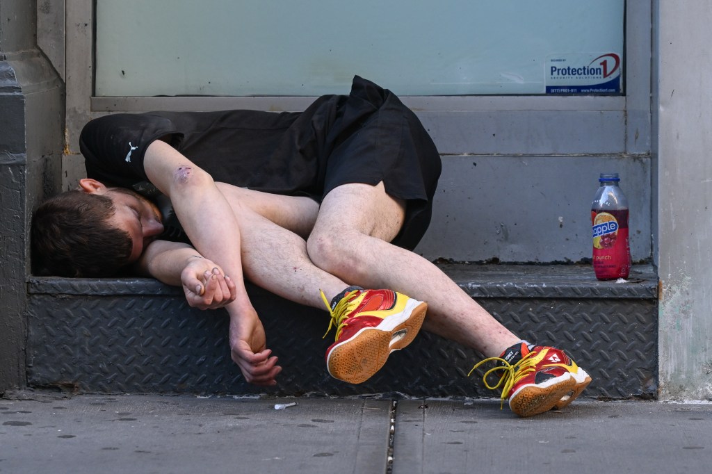 Person sleeping on steps outside a building.