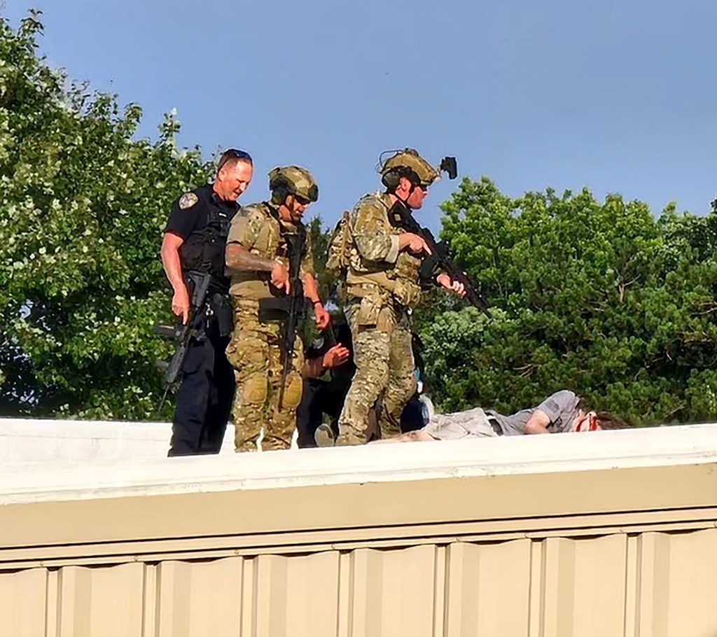 Officers standing over a shooter's body on a rooftop.
