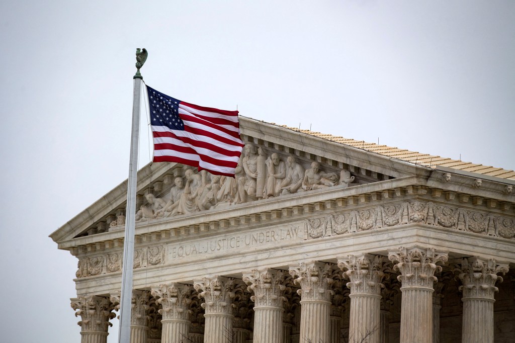 The U.S. Supreme Court building with an American flag.
