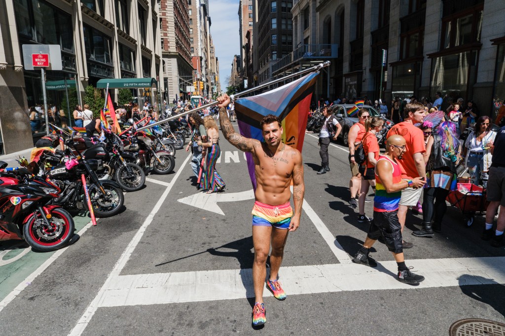 A man at the NYC Pride Parade holds a Pride flag.