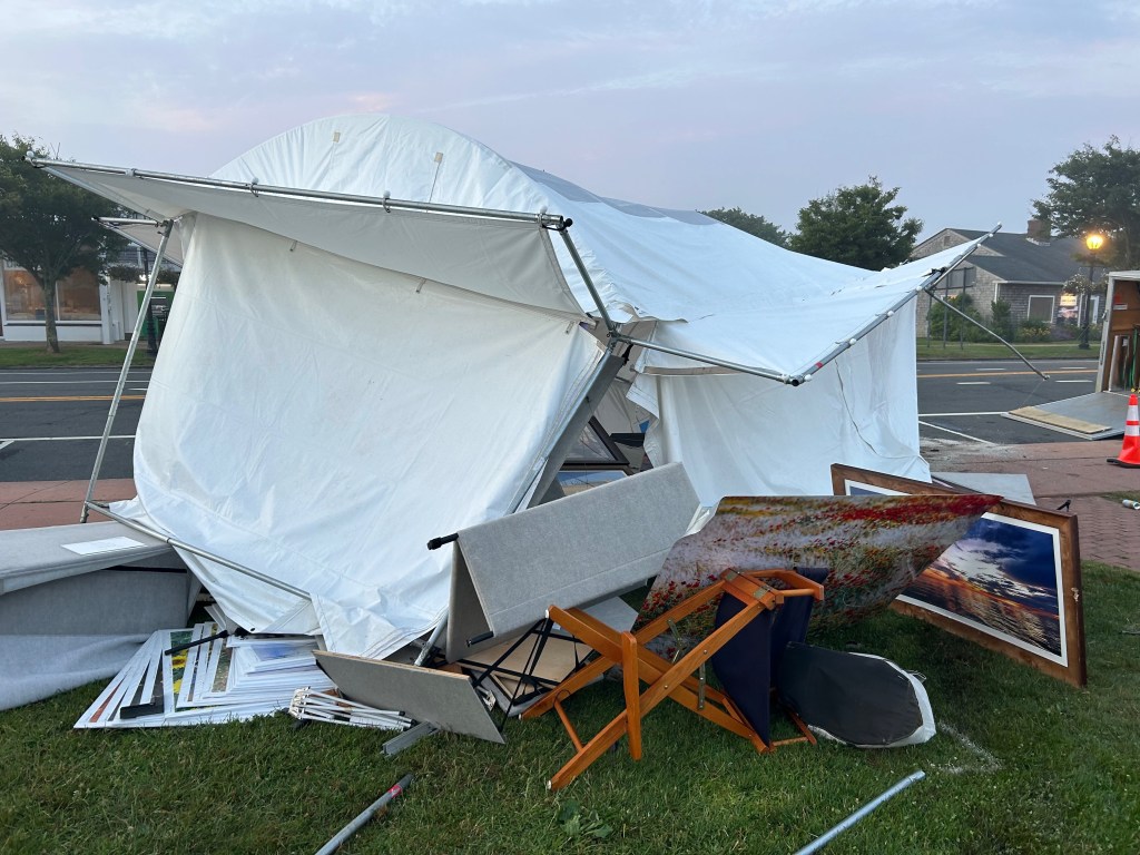 Damaged art show tent and artwork on the ground.