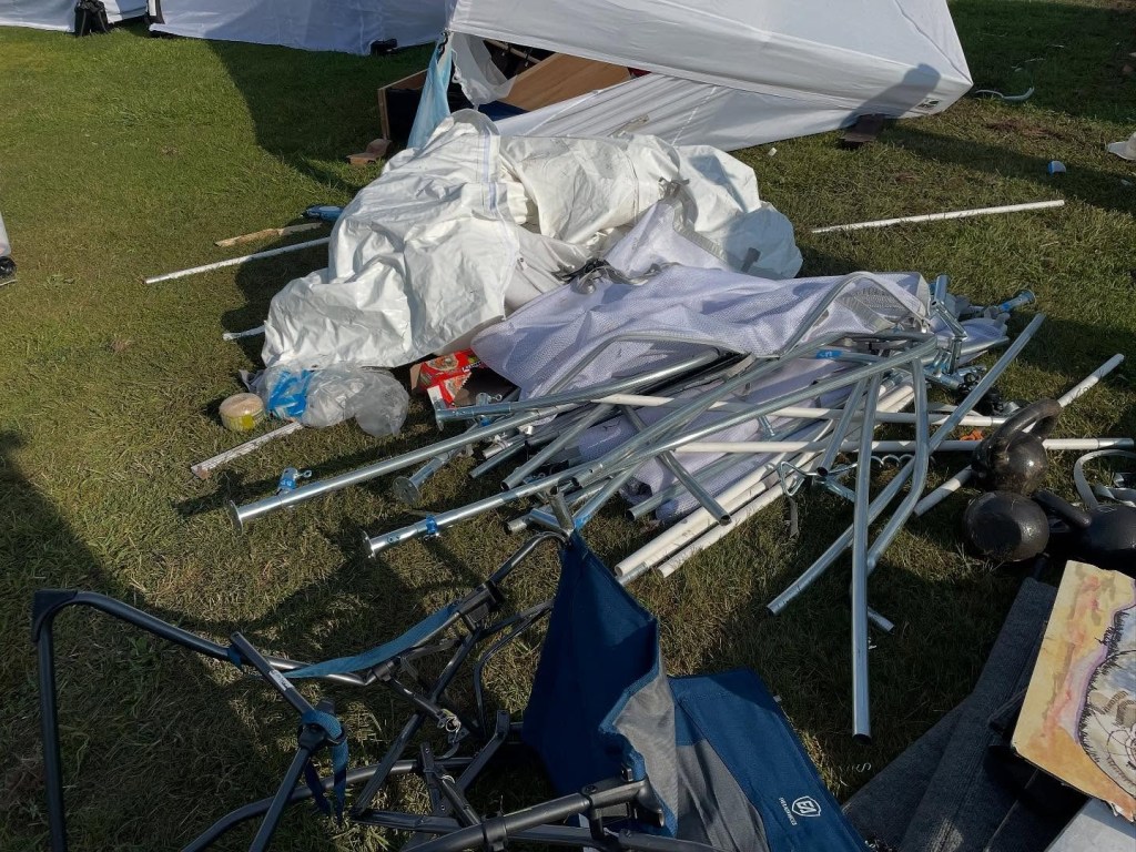 Damaged art show tent and equipment on the ground.