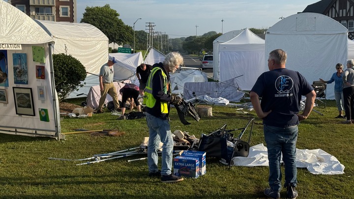 People cleaning up the aftermath of a damaged art show.