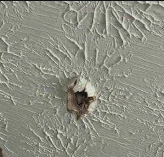 Hole in house siding possibly caused by meteor debris.