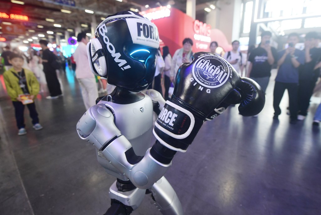 A UNITREE G1 humanoid robot wearing boxing gloves and headgear.